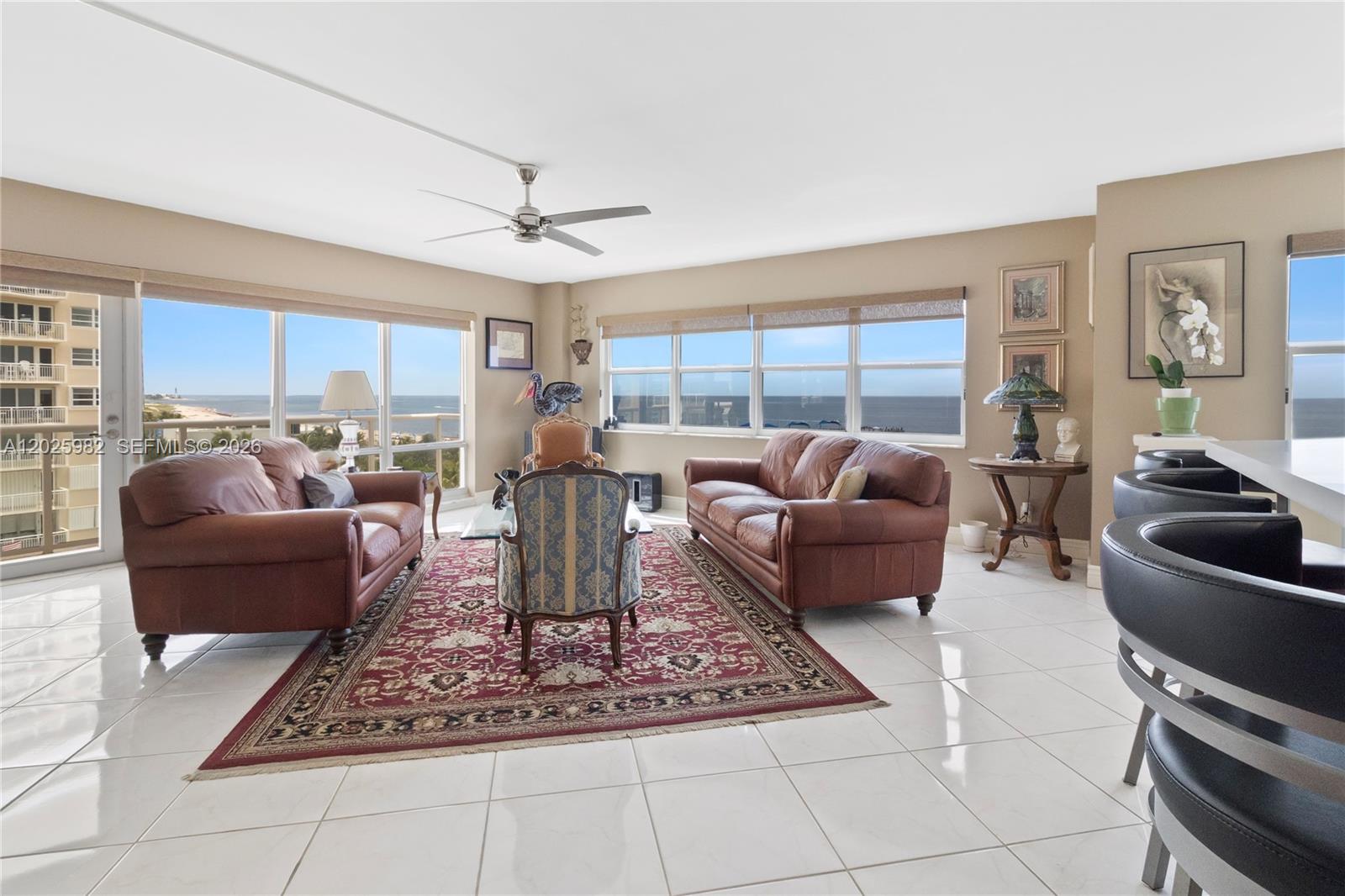 A living room features leather sofas, a patterned rug, and large windows overlooking the ocean — 111 N Pompano Beach Blvd # 909, Pompano Beach FL 33062, POMPANO BEACH, FL
