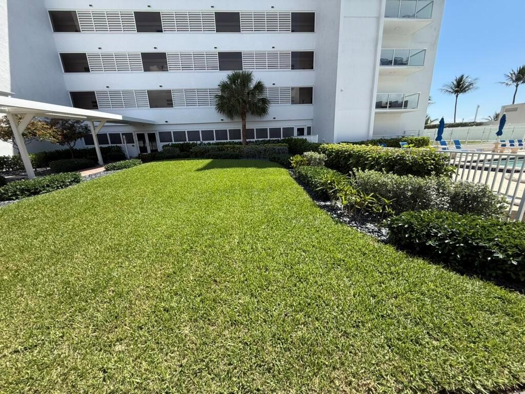 A manicured lawn sits in front of a white multi-story building with a palm tree — 2909 S Ocean Boulevard # 6a, Highland Beach FL 33487, HIGHLAND BEACH, FL