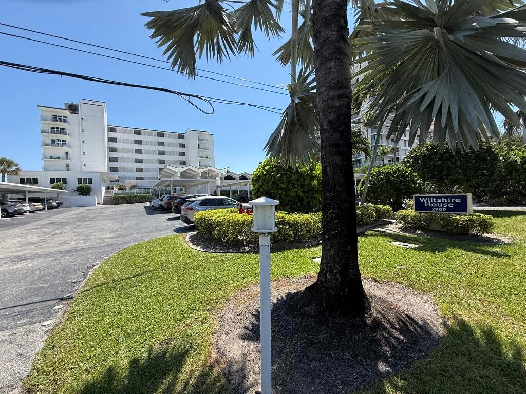 A parking lot sits in front of a multi-story apartment building with palm trees — 2909 S Ocean Boulevard # 6a, Highland Beach FL 33487, HIGHLAND BEACH, FL