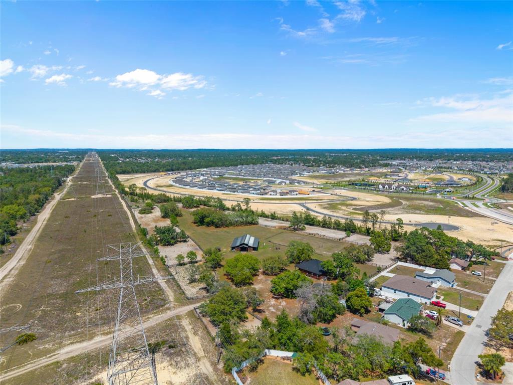An aerial view shows a power line corridor, residential homes, and a large construction site — 3450 GRETNA DRIVE, SPRING HILL, FL