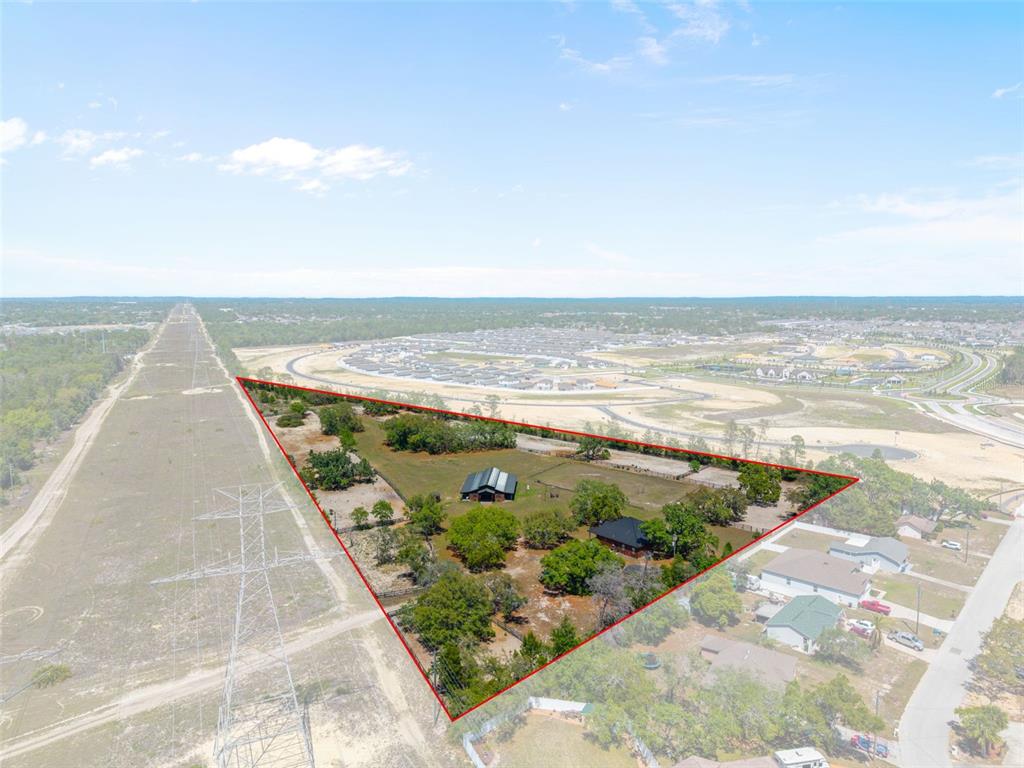 An aerial view shows a triangular property with two buildings surrounded by trees and fields — 3450 GRETNA DRIVE, SPRING HILL, FL