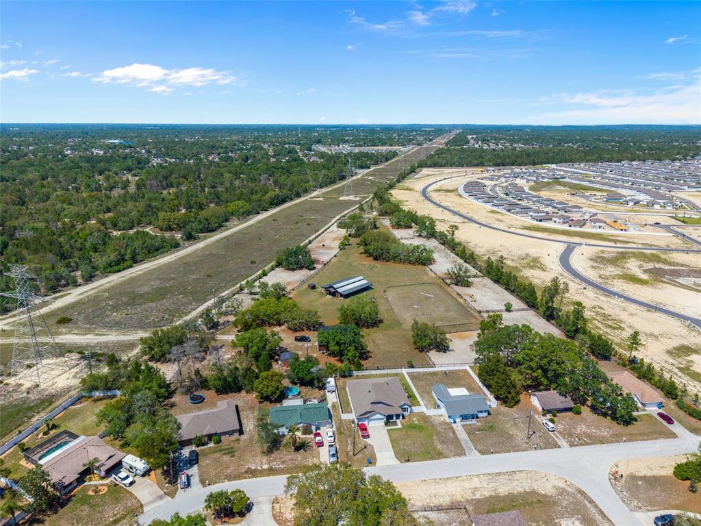 An aerial view shows several suburban houses, a large barn, and a power line corridor — 3450 GRETNA DRIVE, SPRING HILL, FL