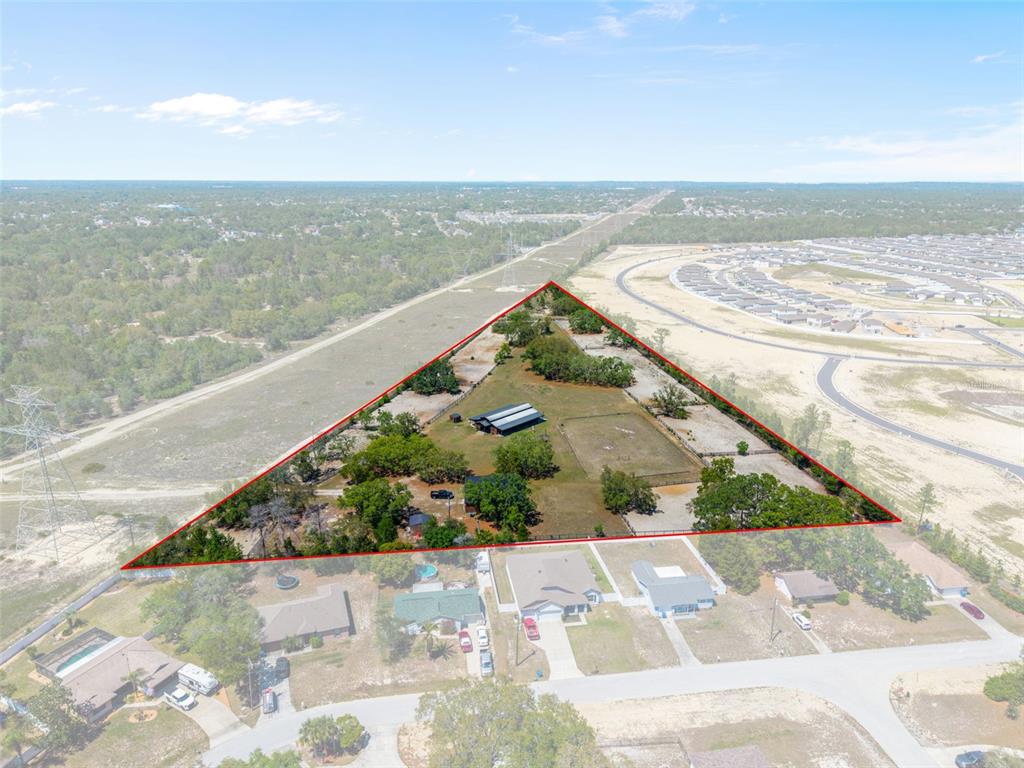 An aerial view shows a triangular fenced property with a barn and trees — 3450 GRETNA DRIVE, SPRING HILL, FL
