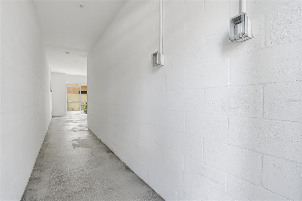 A narrow hallway with white painted concrete block walls and a gray concrete floor — 5523 YELLOWFIN COURT, NEW PORT RICHEY, FL