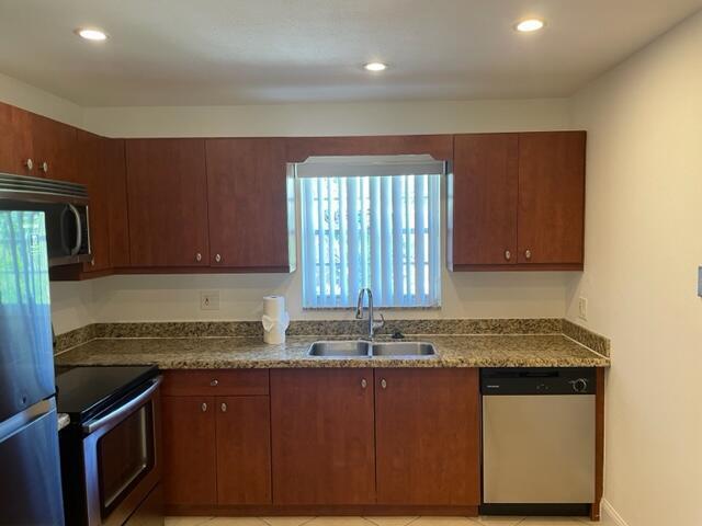 A kitchen features wood cabinets, granite countertops, a stainless steel dishwasher, and a window — 1971 Juno Road, North Palm Beach FL 33408, NORTH PALM BEACH, FL
