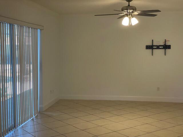 An empty room with tile flooring, a ceiling fan, and a wall-mounted television bracket — 1971 Juno Road, North Palm Beach FL 33408, NORTH PALM BEACH, FL