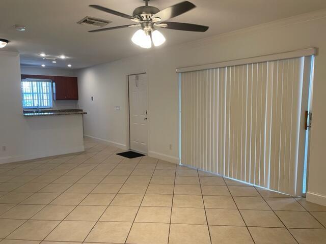 A living area with tile flooring, a ceiling fan, and a sliding glass door — 1971 Juno Road, North Palm Beach FL 33408, NORTH PALM BEACH, FL