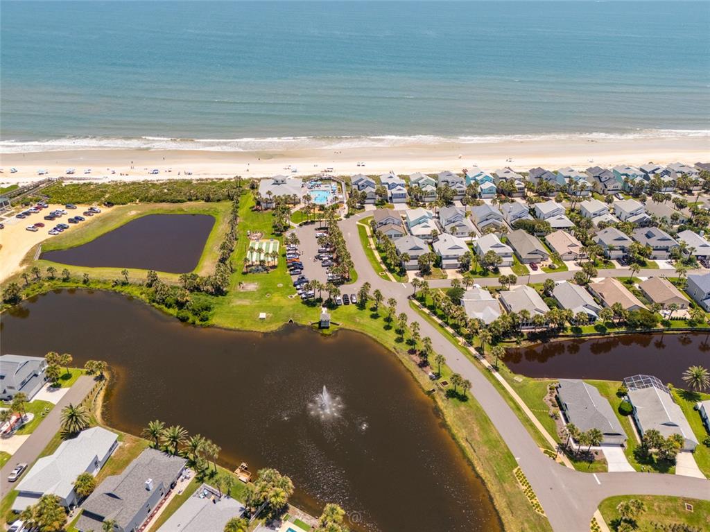 An aerial view shows a coastal neighborhood with houses, ponds, and a beach — 50 NANTUCKET DRIVE, PALM COAST, FL