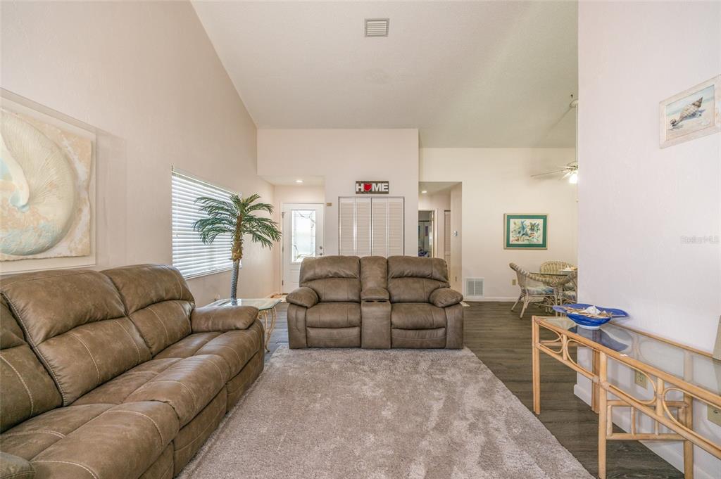A living room features brown leather sofas, a gray area rug, and vaulted ceilings — 50 NANTUCKET DRIVE, PALM COAST, FL