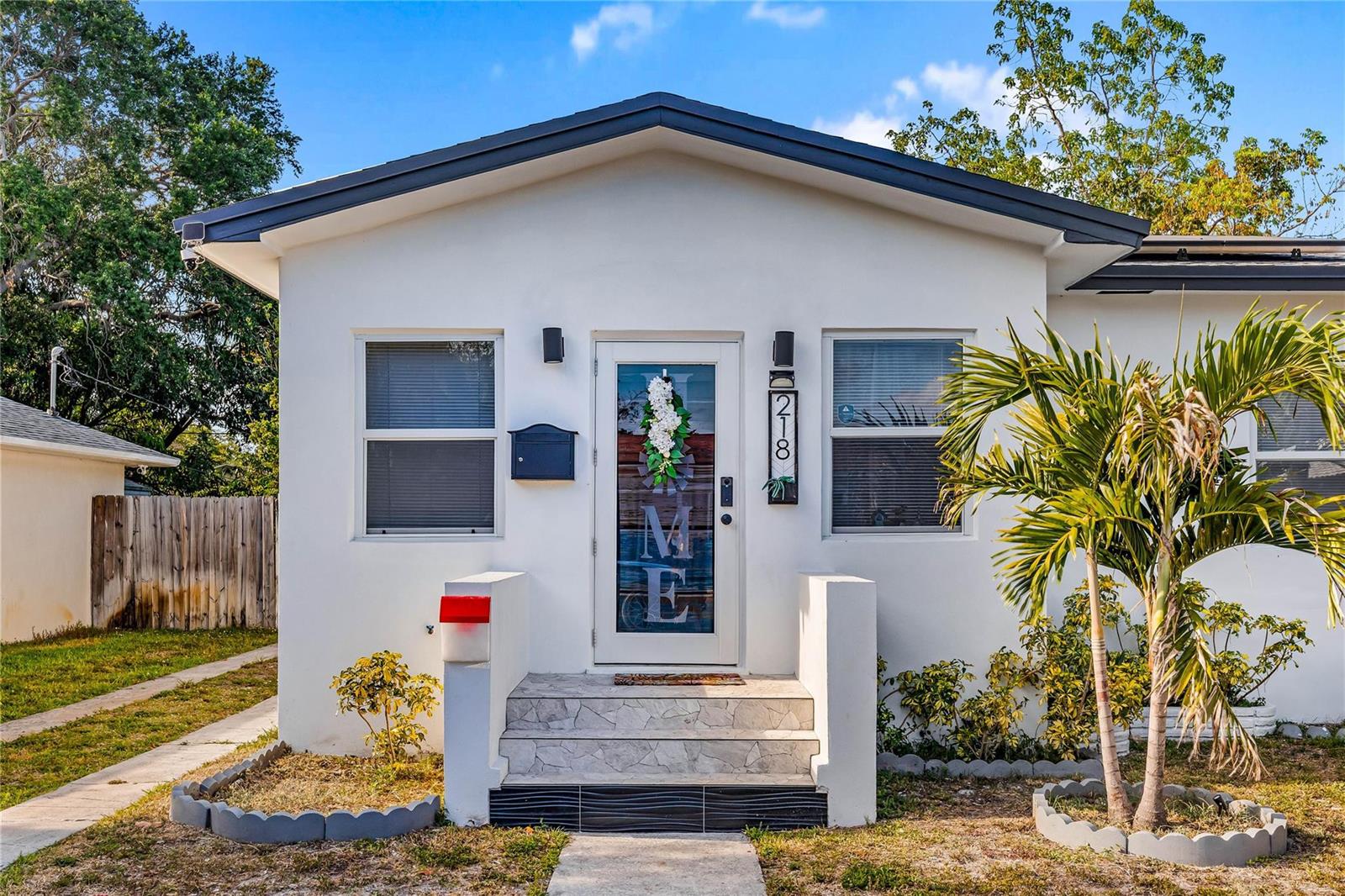 The exterior of a white house features a front door with a wreath and steps — 218 SW 7th Street, Dania Beach FL 33004, DANIA BEACH, FL