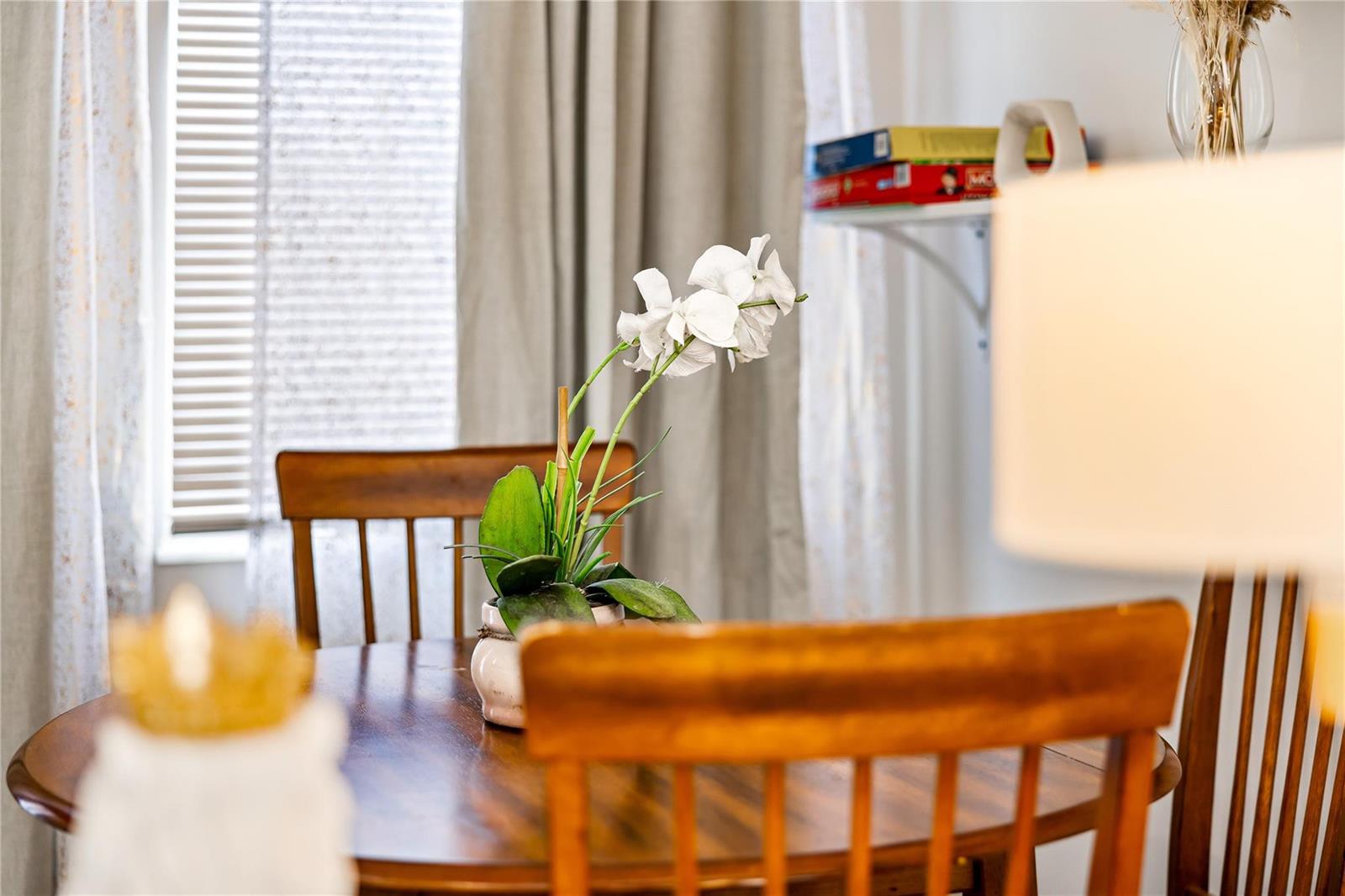 A wooden dining table with a white orchid centerpiece sits in front of a window — 218 SW 7th Street, Dania Beach FL 33004, DANIA BEACH, FL