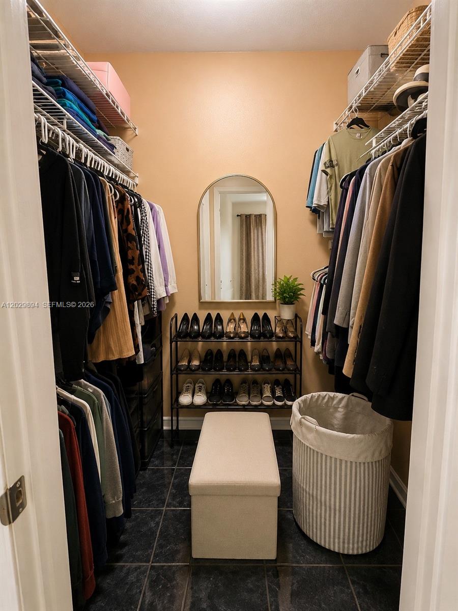 A walk-in closet features hanging clothes, a shoe rack, a bench, and a mirror — 6850 W 16th Dr # 317, Hialeah FL 33014, HIALEAH, FL