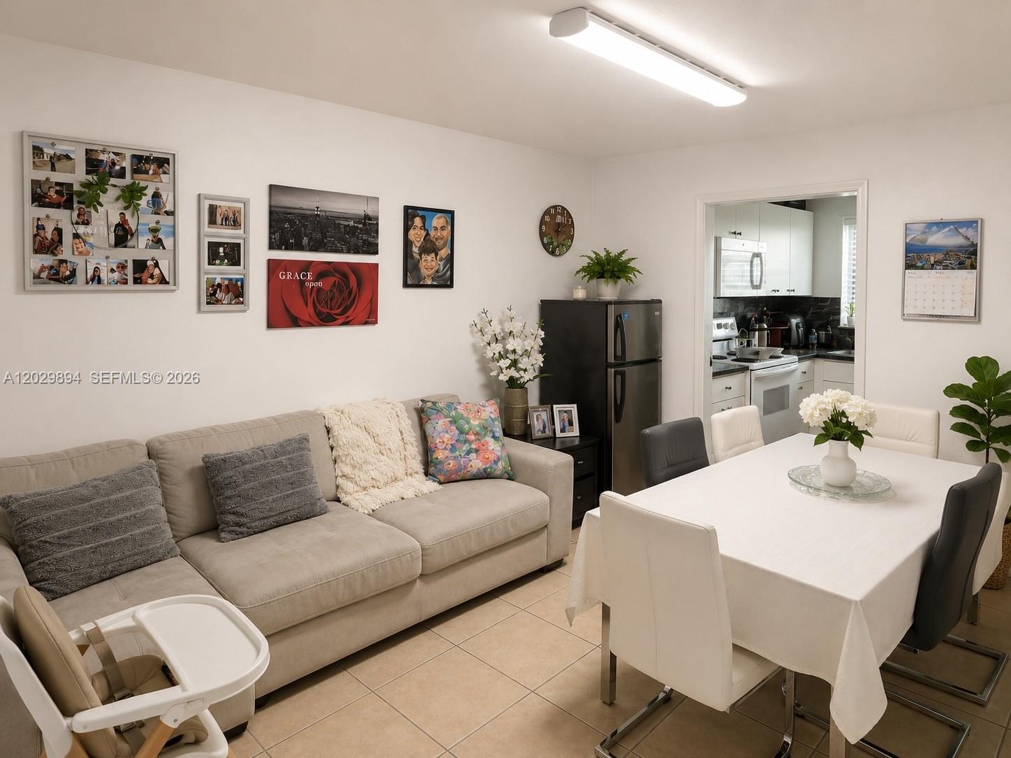 A living and dining area features a beige sofa, a white dining table, and tile flooring — 6850 W 16th Dr # 317, Hialeah FL 33014, HIALEAH, FL