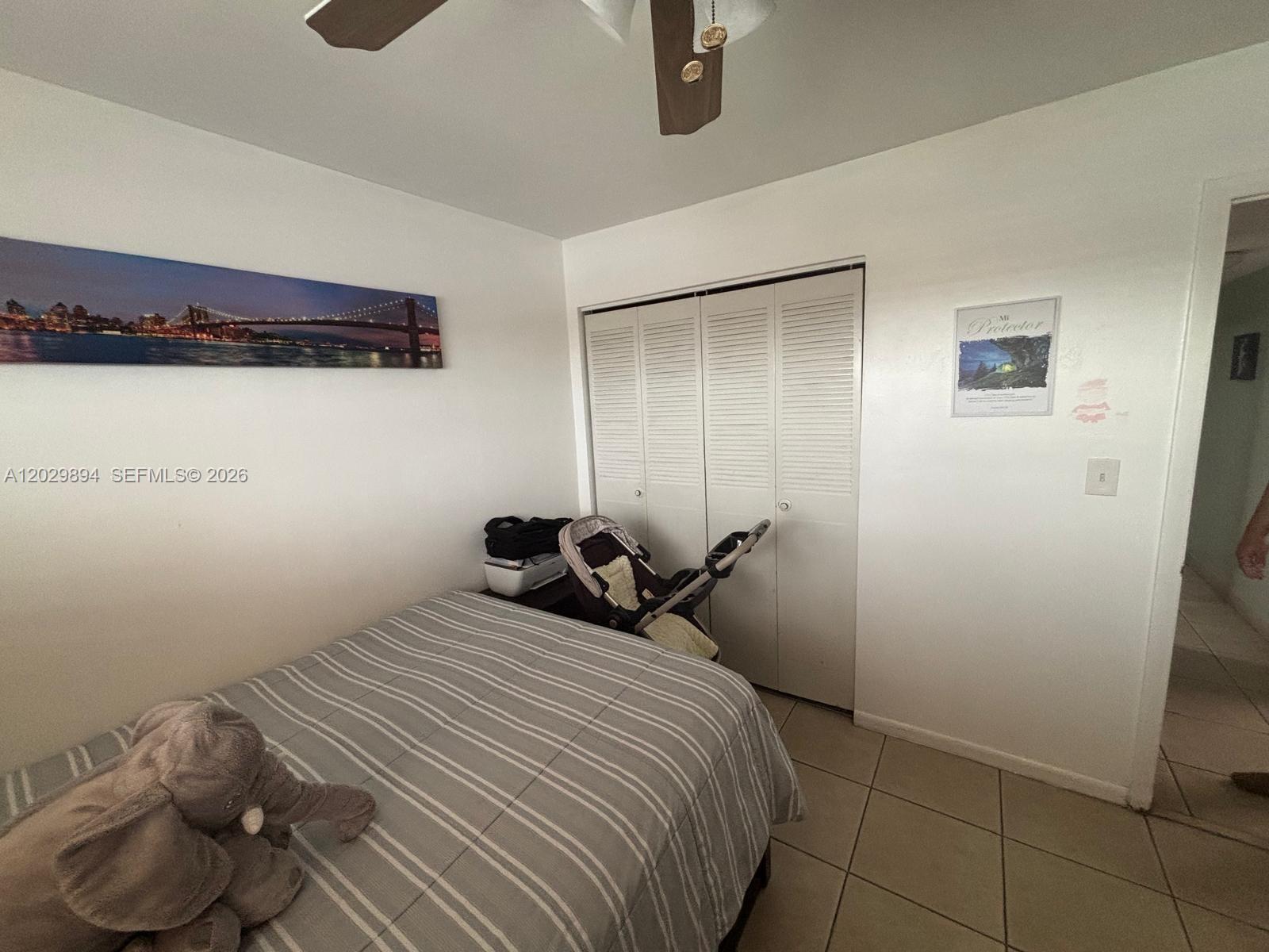 A bedroom features a bed with a striped comforter, a closet, and a ceiling fan — 6850 W 16th Dr # 317, Hialeah FL 33014, HIALEAH, FL