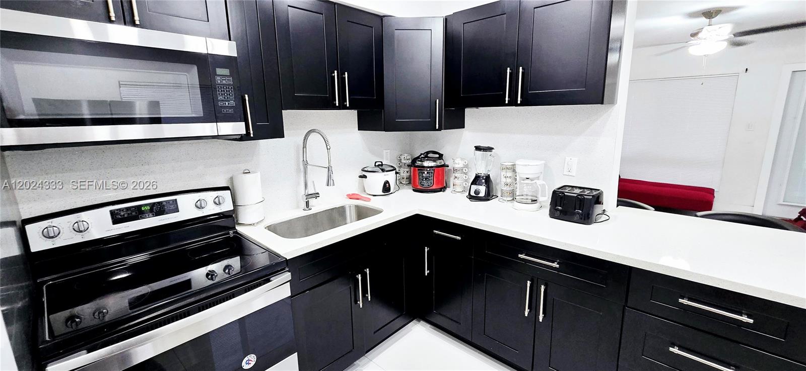 A kitchen features black cabinets, white countertops, a stainless steel sink, and stainless steel appliances — 139 NW 14th Way, Dania Beach FL 33004, DANIA BEACH, FL