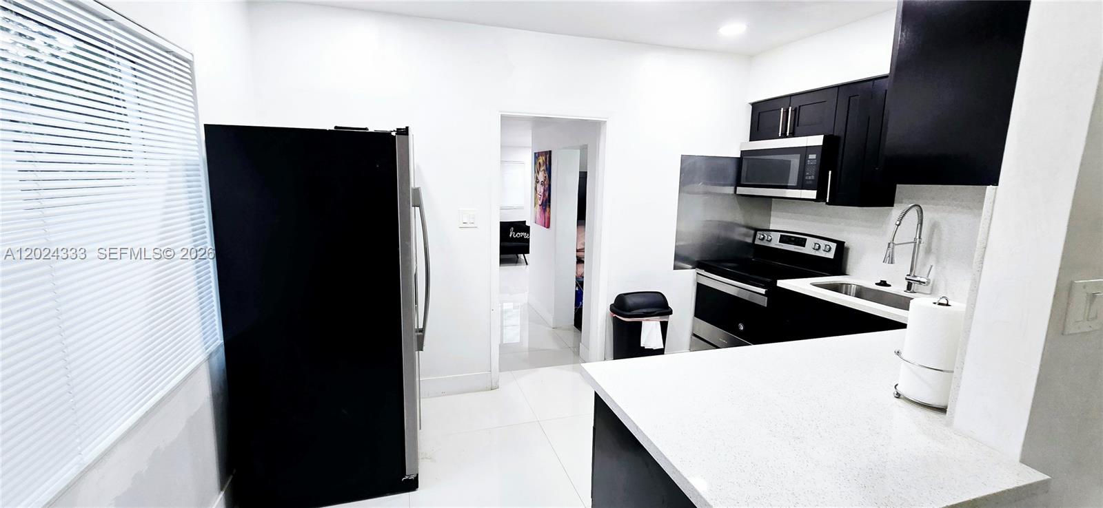 A kitchen features black cabinets, stainless steel appliances, and a white countertop — 139 NW 14th Way, Dania Beach FL 33004, DANIA BEACH, FL