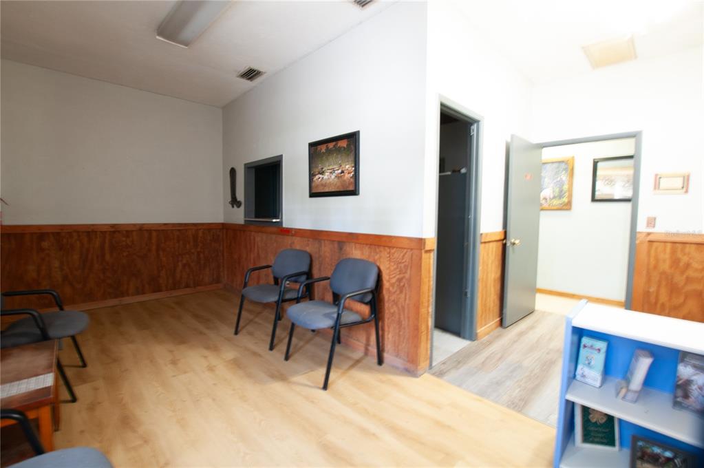 A waiting room features light wood flooring, wood wainscoting, gray chairs, and two open doorways — 2865 SE HIGHWAY 31, ARCADIA, FL
