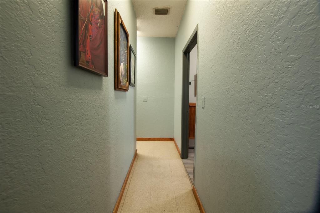A narrow hallway features light blue walls, framed artwork, and light-colored tile flooring — 2865 SE HIGHWAY 31, ARCADIA, FL