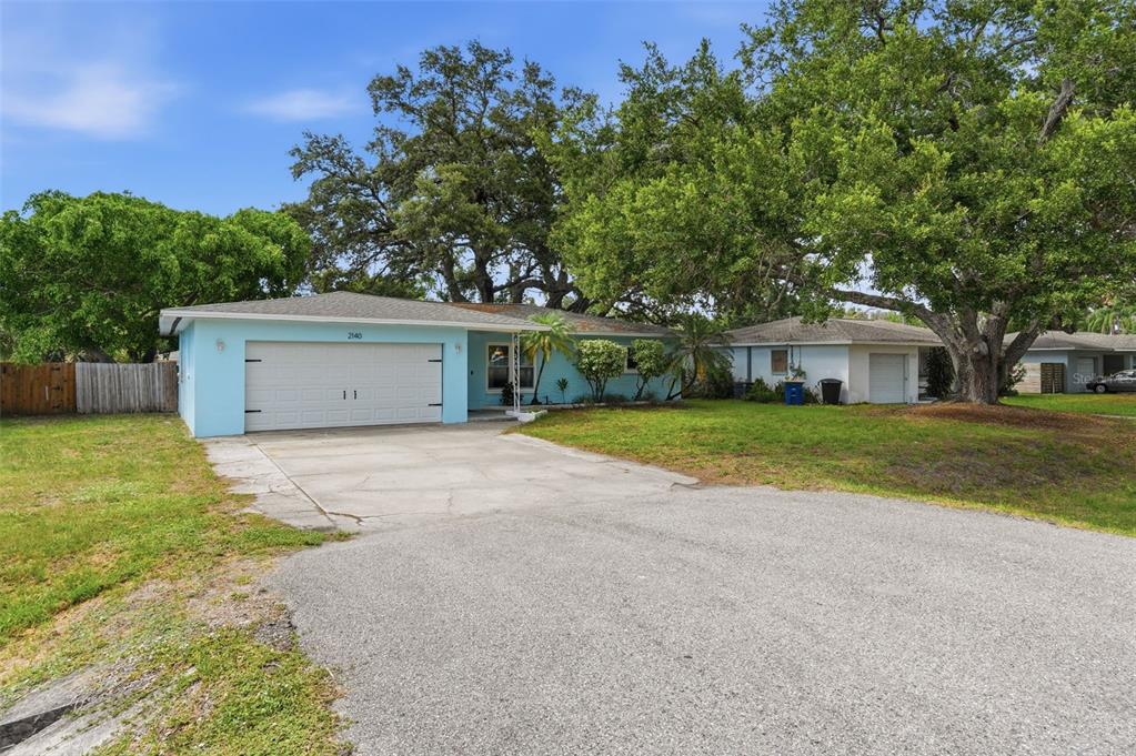 A light blue single-story house with a two-car garage and a large front yard — 2140 NE COACHMAN ROAD, CLEARWATER, FL