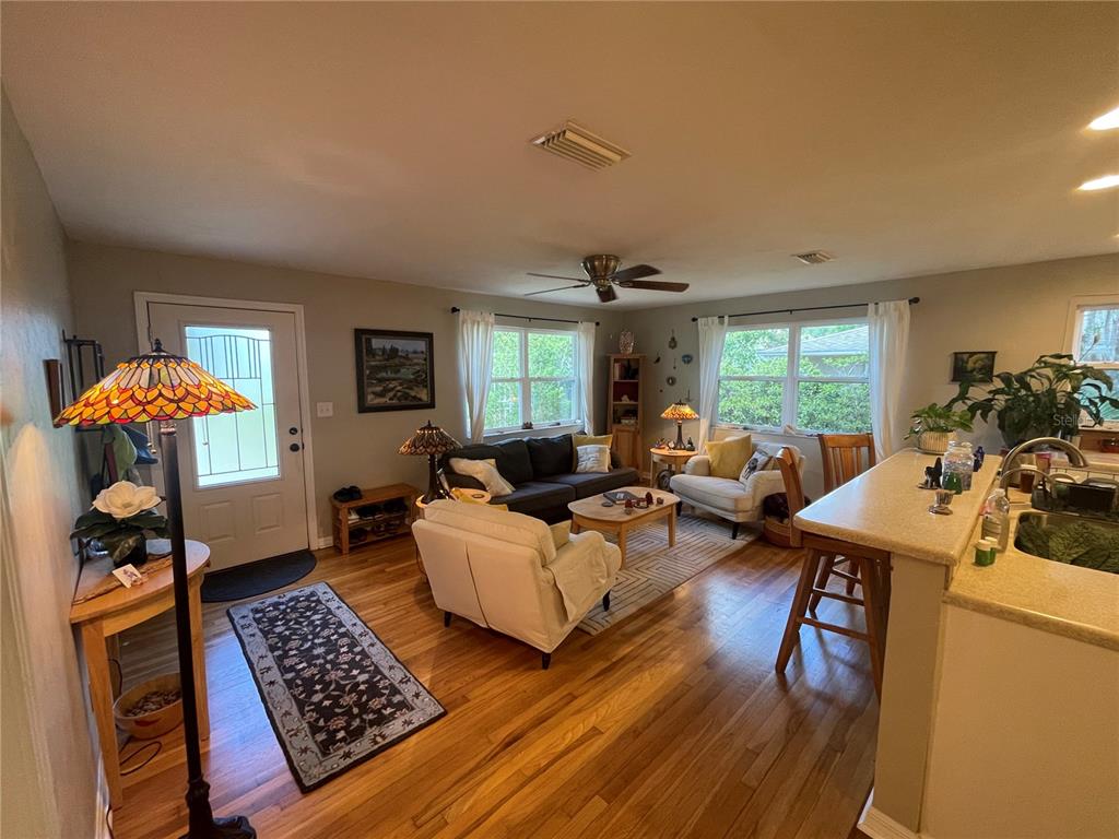 A living room with hardwood floors, a ceiling fan, and an open kitchen counter — 1317 NW 4TH STREET, GAINESVILLE, FL