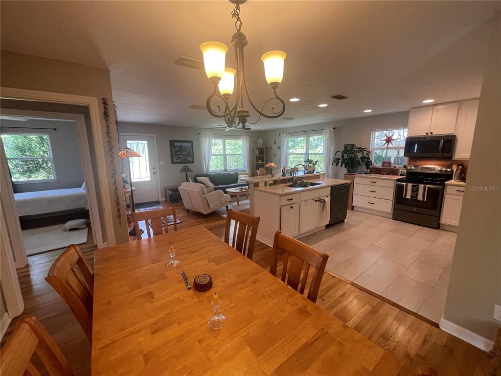A dining area with a wooden table leads into an open-concept kitchen and living room — 1317 NW 4TH STREET, GAINESVILLE, FL