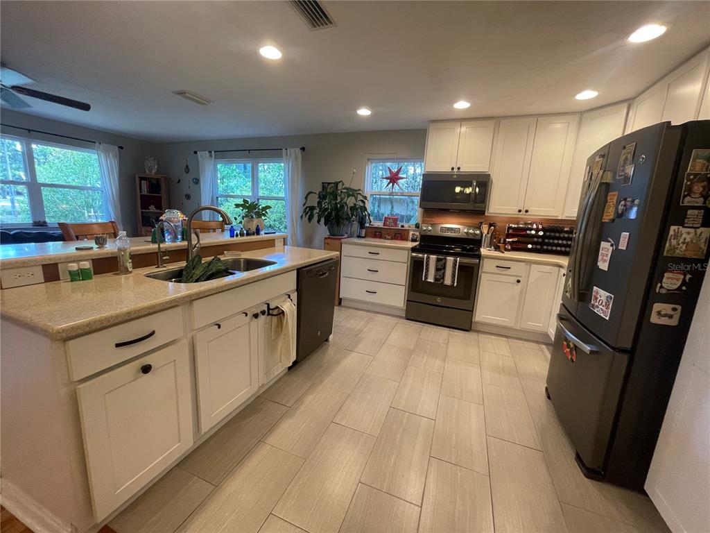 A kitchen with white cabinets, stainless steel appliances, a center island, and light tile flooring — 1317 NW 4TH STREET, GAINESVILLE, FL