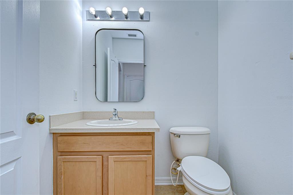 A bathroom features a wooden vanity, a sink, a mirror, and a toilet — 7809 TUSCANY WOODS DRIVE, TAMPA, FL