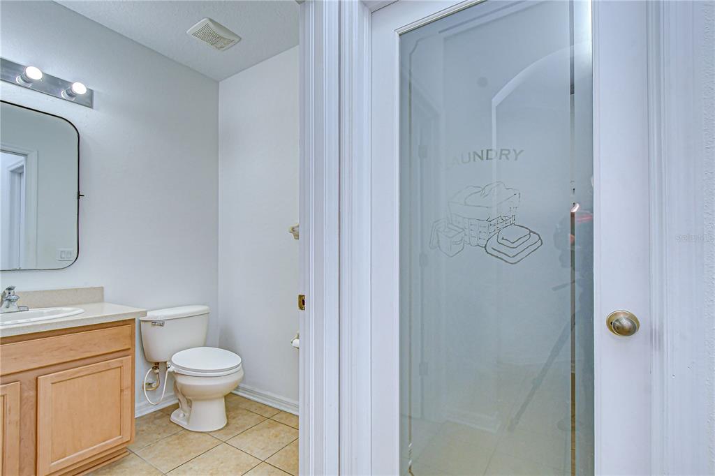 A bathroom with a vanity and toilet sits next to a door labeled laundry — 7809 TUSCANY WOODS DRIVE, TAMPA, FL