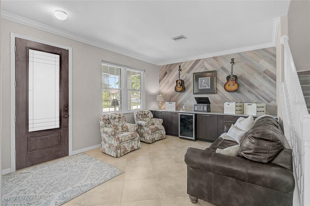 A living room features a dark wood door, tile floors, a sofa, and two armchairs — 20275 GRANLAGO DRIVE, VENICE, FL