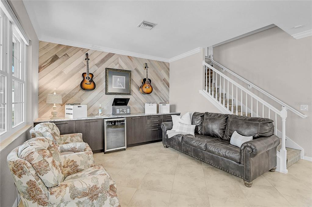 A living room features a wood-paneled accent wall with two guitars, cabinetry, and a staircase — 20275 GRANLAGO DRIVE, VENICE, FL