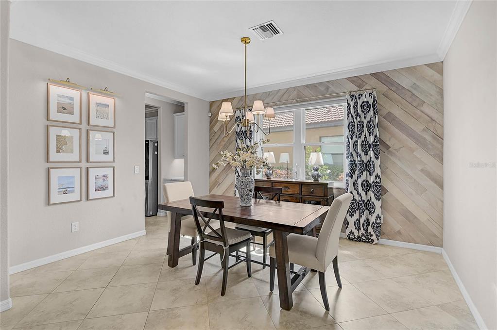 A dining room features a wooden table, chairs, a chandelier, and a diagonal wood-paneled wall — 20275 GRANLAGO DRIVE, VENICE, FL
