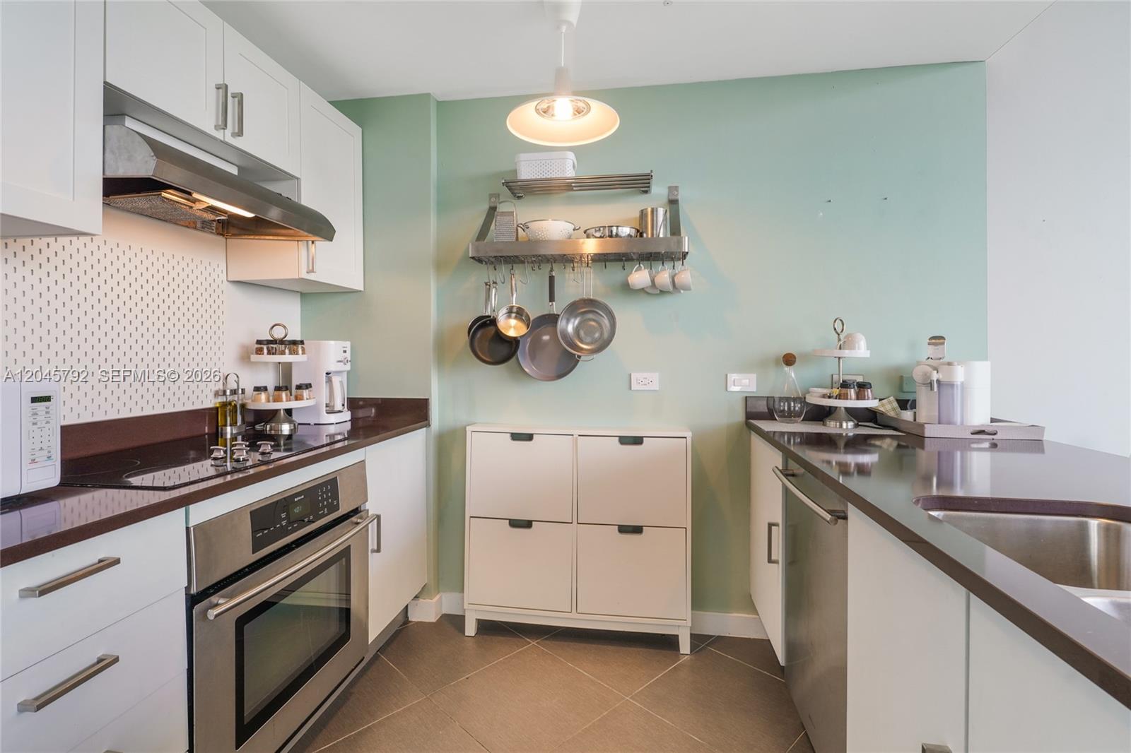 A kitchen features white cabinets, dark countertops, a stainless steel oven, and a hanging rack — 3301 NE 1st Ave # M0705, Miami FL 33137, MIAMI, FL