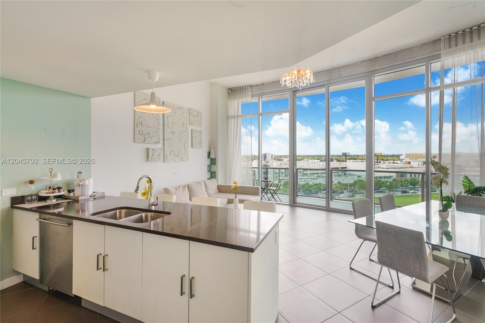 A modern open-concept living and dining area features a kitchen island and floor-to-ceiling windows — 3301 NE 1st Ave # M0705, Miami FL 33137, MIAMI, FL