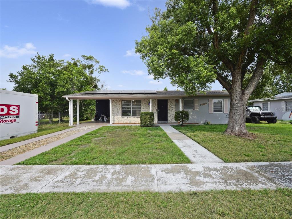 A single-story house with a stone facade, a carport, and solar panels on the roof — 1460 E LOMBARDY DRIVE, DELTONA, FL