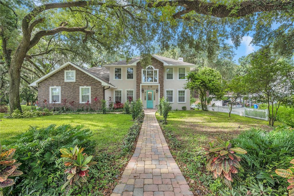 A two-story house with a brick and stucco exterior, a turquoise front door, and trees — 1507 W WINDHORST ROAD, BRANDON, FL
