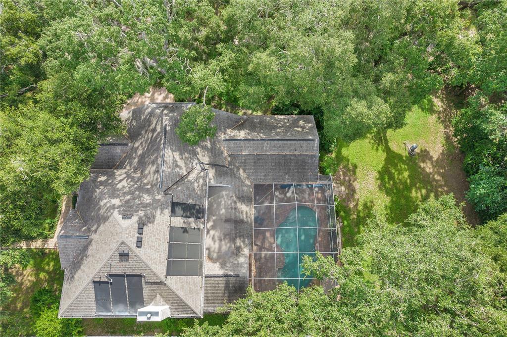 An aerial view shows a house with a screened-in pool and solar panels on the roof — 1507 W WINDHORST ROAD, BRANDON, FL