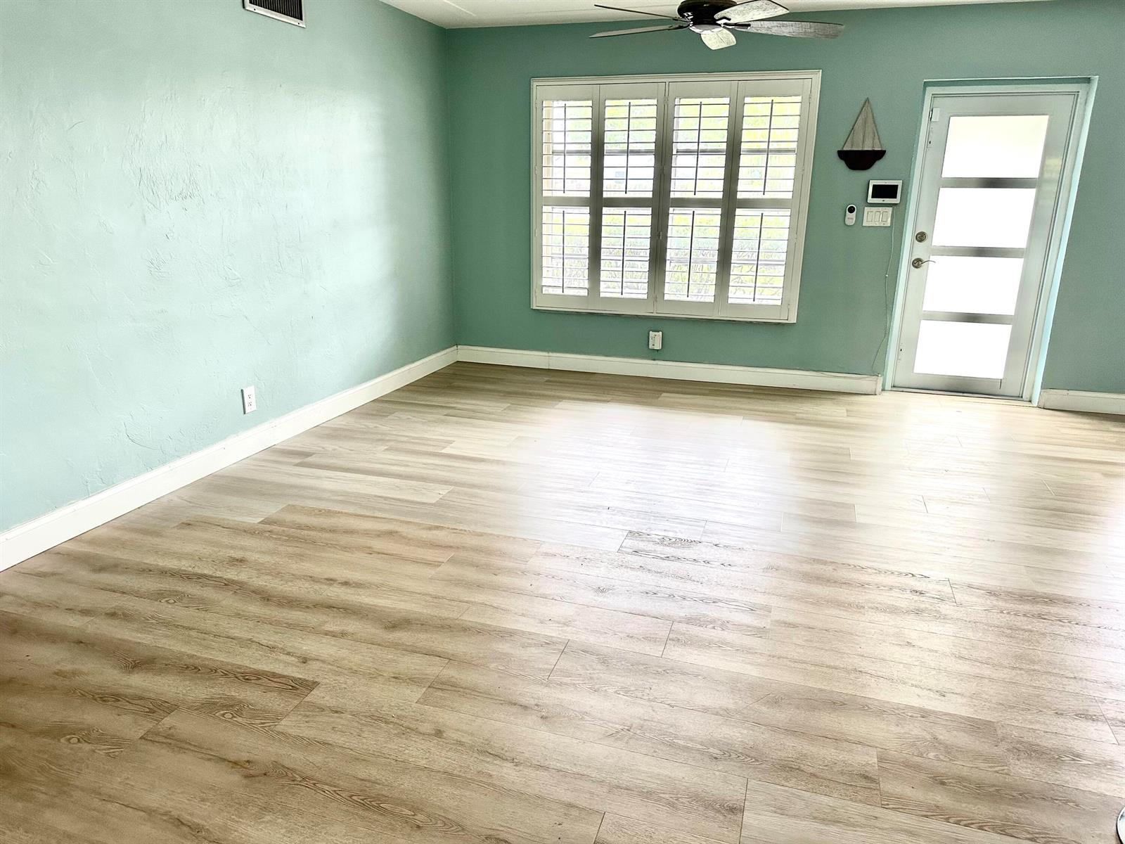 An empty room features light green walls, wood-look flooring, a ceiling fan, and plantation shutters — 420 SE 12th Avenue, Deerfield Beach FL 33441, DEERFIELD BEACH, FL