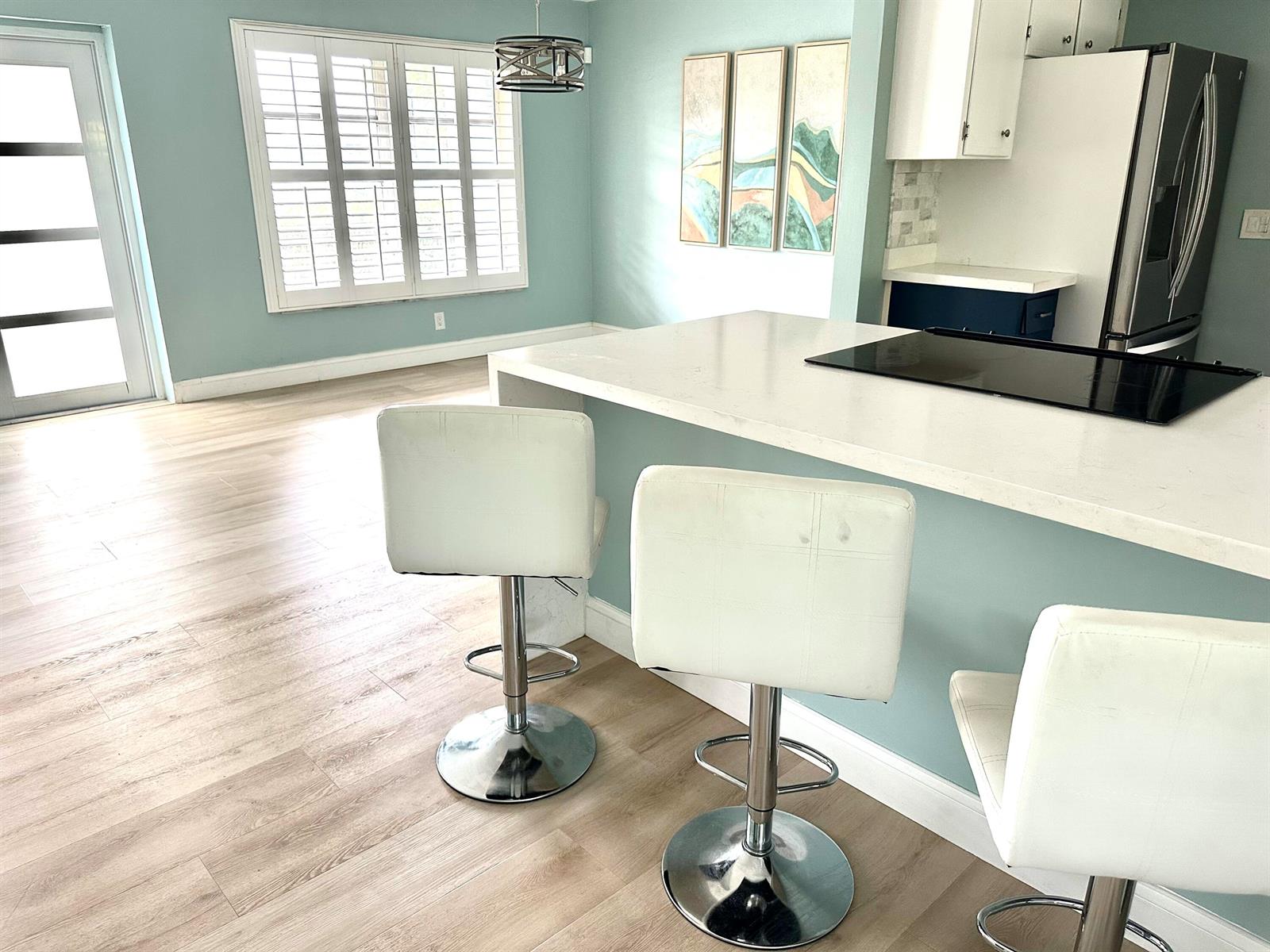 A kitchen features a white island with bar stools, light blue walls, and wood flooring — 420 SE 12th Avenue, Deerfield Beach FL 33441, DEERFIELD BEACH, FL