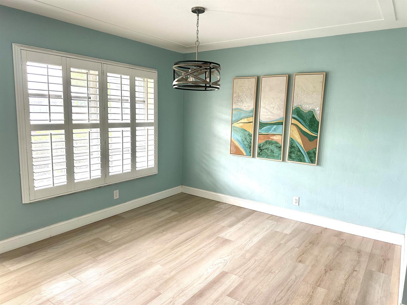 An empty dining room features light blue walls, wood-look flooring, plantation shutters, and a chandelier — 420 SE 12th Avenue, Deerfield Beach FL 33441, DEERFIELD BEACH, FL