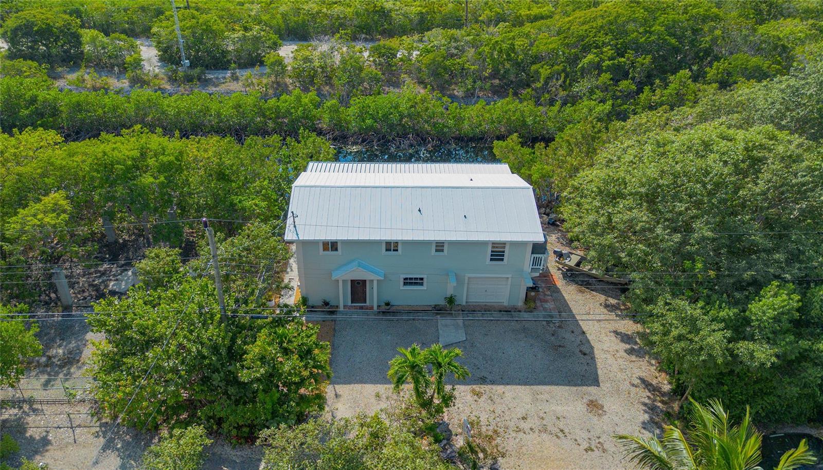 An aerial view shows a two-story house with a metal roof surrounded by dense trees — 133 Valois Boulevard, Key Largo FL 33037, KEY LARGO, FL