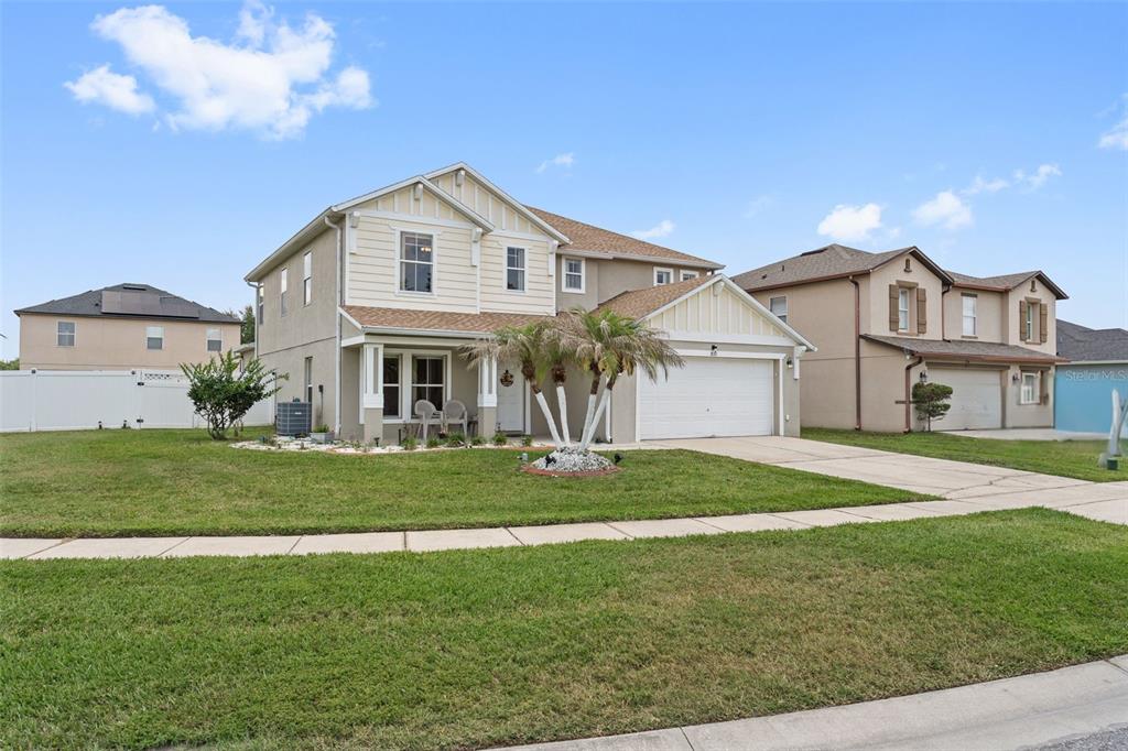 A two-story suburban house with a white garage and palm trees at sunset — 831 NEPTUNE POINTE LANE, KISSIMMEE, FL