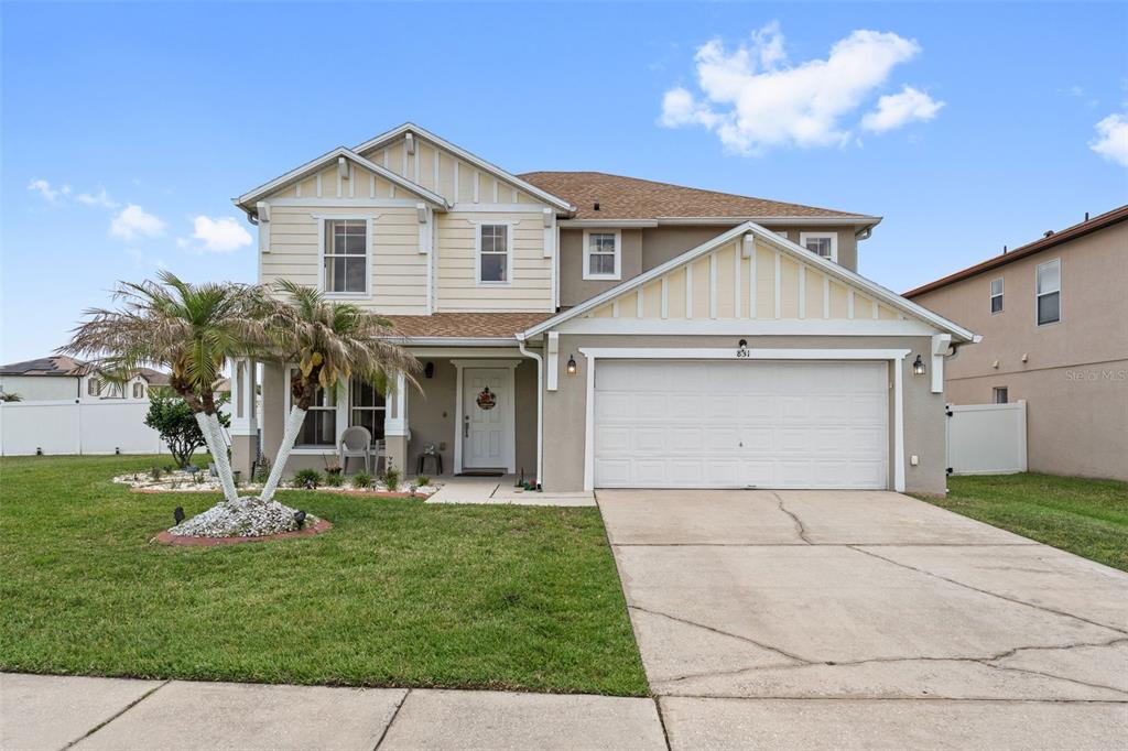A grassy backyard is enclosed by a white vinyl privacy fence under a blue sky — 831 NEPTUNE POINTE LANE, KISSIMMEE, FL