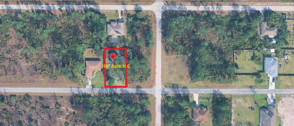 This is an aerial map view showing a vacant residential lot outlined in red — 1057 BELLS STREET E, LEHIGH ACRES, FL