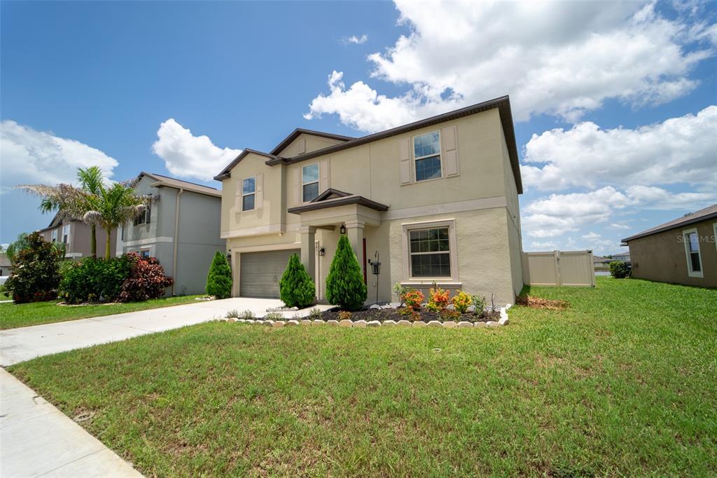 A two-story tan stucco house with a two-car garage and a front lawn — 9831 LEMON DROP LOOP, RUSKIN, FL