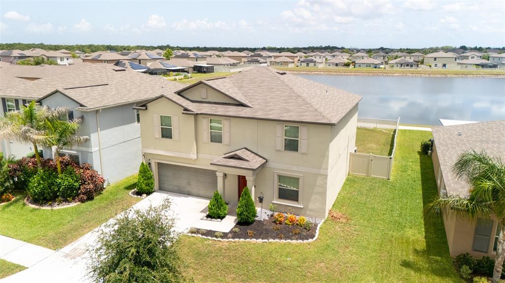 An aerial view shows a two-story suburban house with a garage and a backyard pond — 9831 LEMON DROP LOOP, RUSKIN, FL