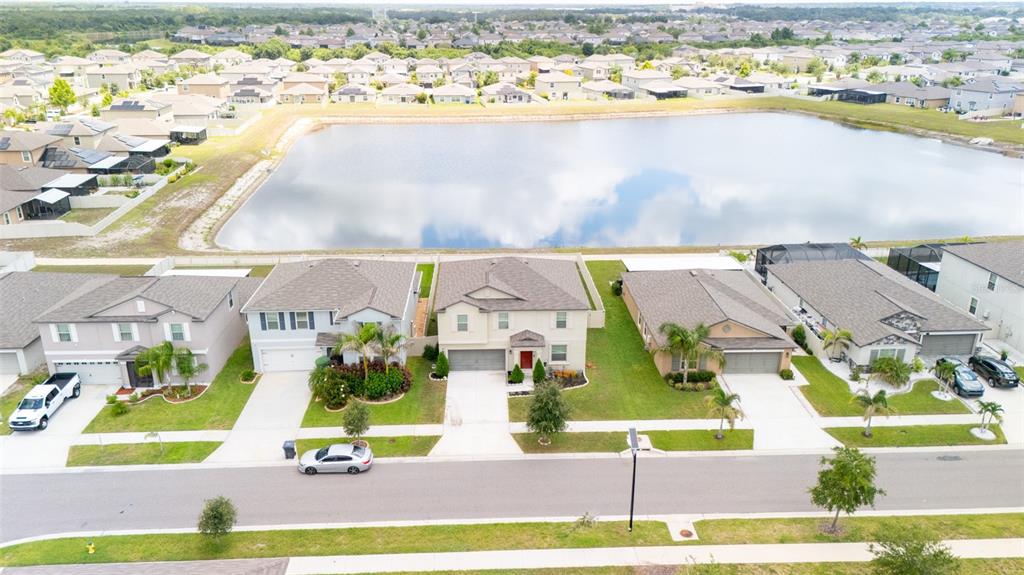 An aerial view shows a row of suburban houses facing a large retention pond — 9831 LEMON DROP LOOP, RUSKIN, FL