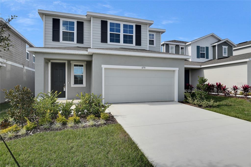 A two-story house with a gray stucco exterior, a two-car garage, and black shutters — 6178 DAPHNE STREET, LAKE HAMILTON, FL
