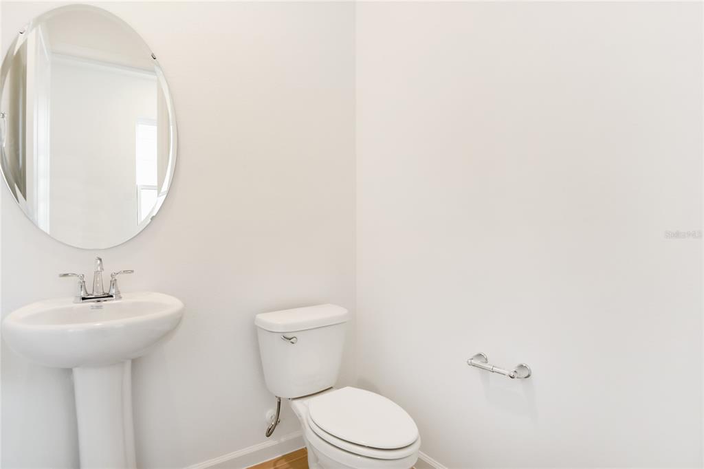 A half bathroom features a pedestal sink, an oval mirror, and a white toilet — 6178 DAPHNE STREET, LAKE HAMILTON, FL