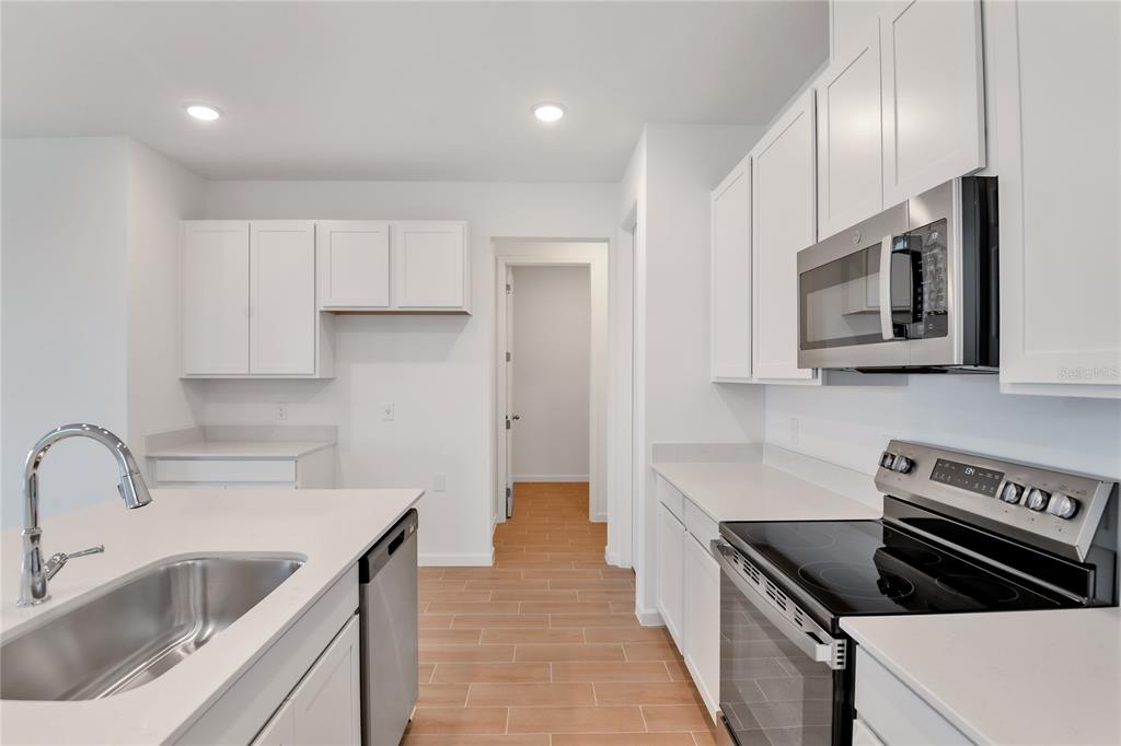 A kitchen features white cabinets, stainless steel appliances, a center island, and light-colored tile flooring — 6178 DAPHNE STREET, LAKE HAMILTON, FL