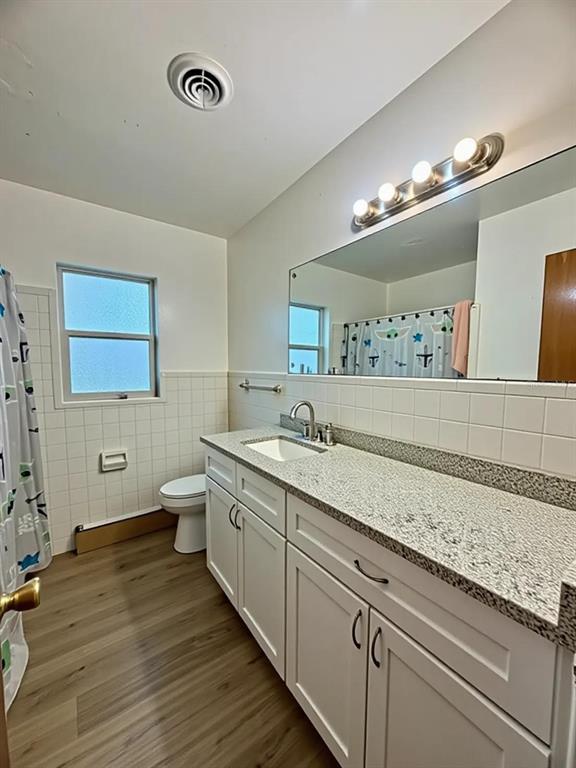 A bathroom features a white vanity with a granite countertop, a large mirror, and wood-look flooring — 5235 SE 107TH STREET, BELLEVIEW, FL